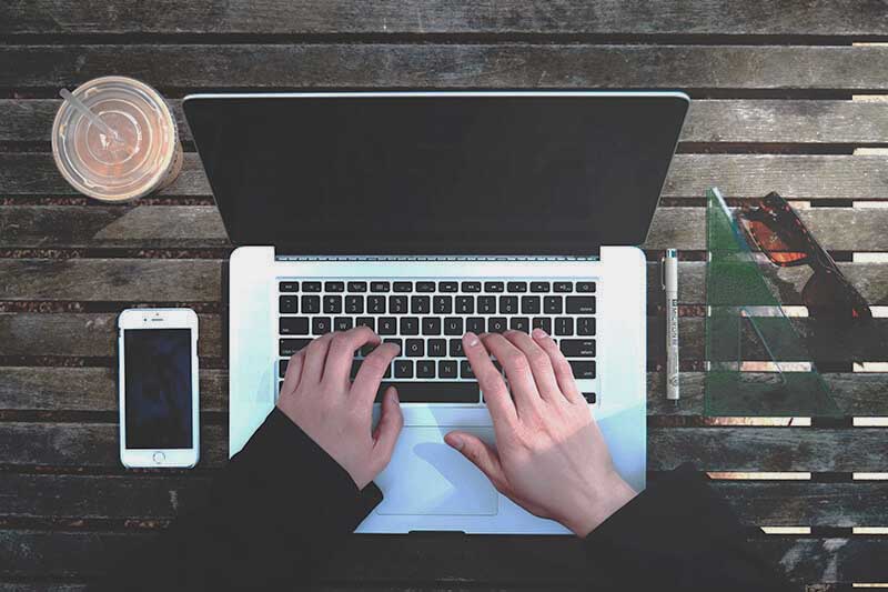 Hands of an AI prompter typing on a laptop